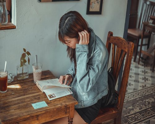 A person gently stretching shoulders backward at a cozy cafe table