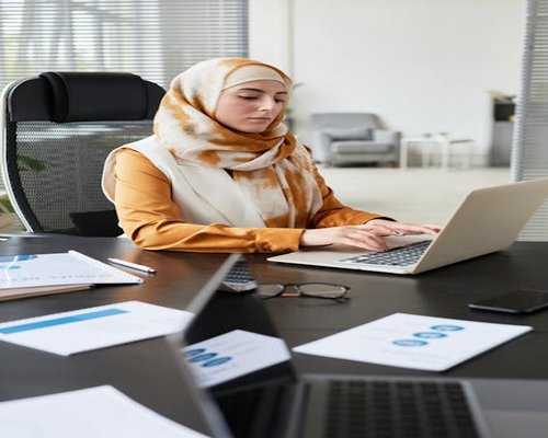 Smiling editorial team member typing on a laptop